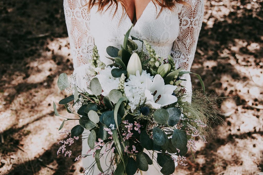 Weißer Blumenstrauss in den Händen der Braut