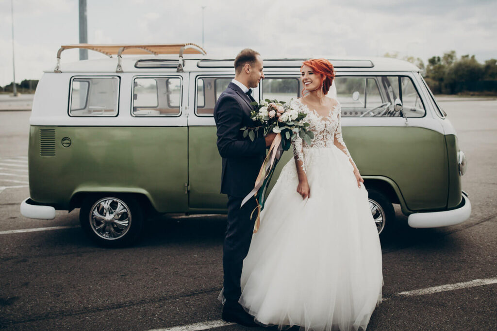 Das Hochzeitspaar vor einem Bulli als Hochzeitsauto